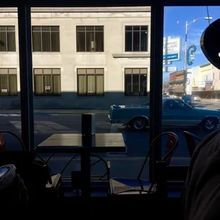 a man in a hat sitting at a table looking out a window