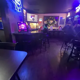 a bar with purple lighting and a neon sign