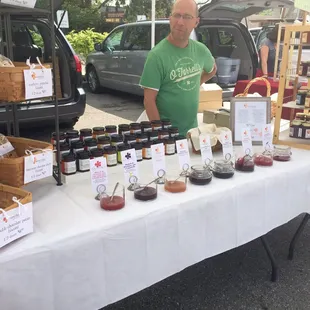 a man standing in front of a table with jars of jams