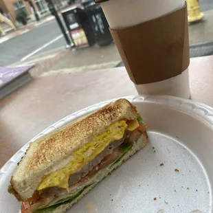 a half eaten sandwich and a cup of coffee