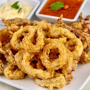 a plate of fried onion rings with dipping sauce