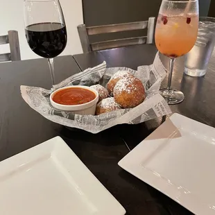 a table with a bowl of soup, a plate of donuts, and a glass of wine