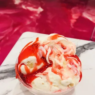Toasted coconut and Strawberry cheesecake ice cream with strawberry drizzle on top, Oreo and strawberry drizzle are also on the bottom