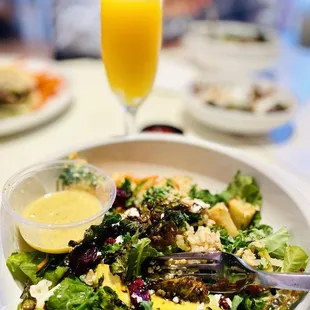 a plate of salad and a glass of orange juice