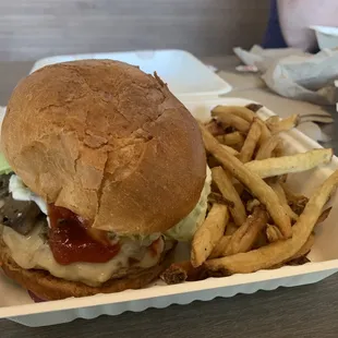 a burger and fries in a styrofoam container