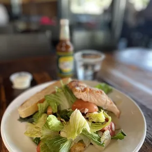 a sandwich with lettuce, tomatoes, and a side salad