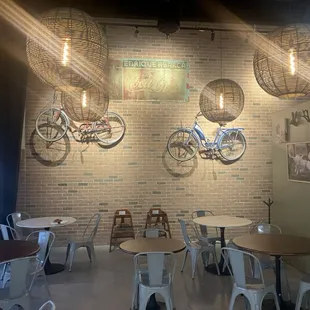 a room with tables, chairs, and bicycles on the wall