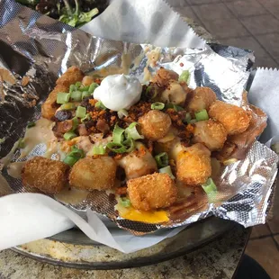 Tot-mess loaded tater tots. Swimming in cheese sauce topped with bacon.