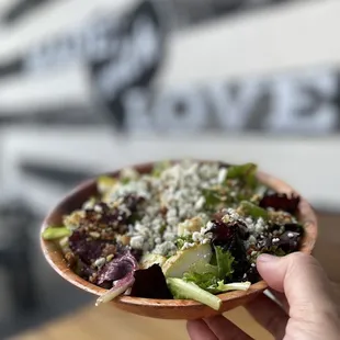 a hand holding a bowl of salad