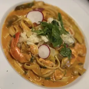 a plate of pasta with shrimp and radishes