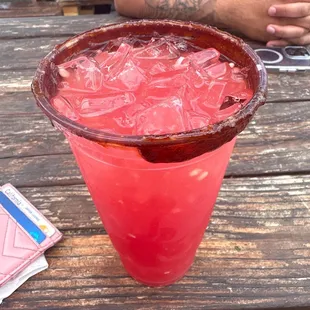 a man sitting at a picnic table with a red drink