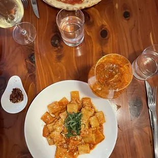 a table with a pizza and a glass of wine