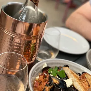 a bowl of mussels, bread, and a bottle of wine