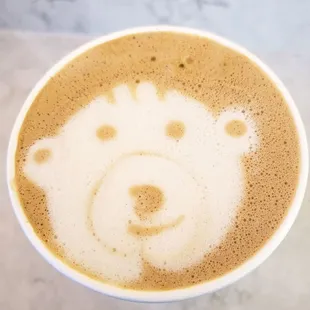 a cup of cappuccino with a bear drawn on it