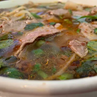  a bowl of soup with meat and vegetables