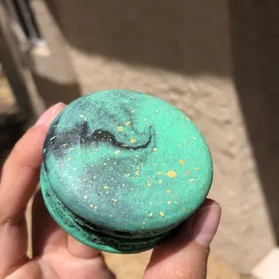 a hand holding a green macaron