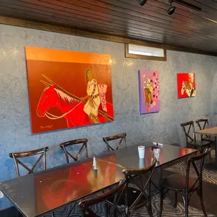 tables and chairs with paintings on the wall