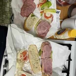 two sub sandwiches on wax paper on a stove