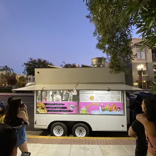 a group of people standing in front of a food truck