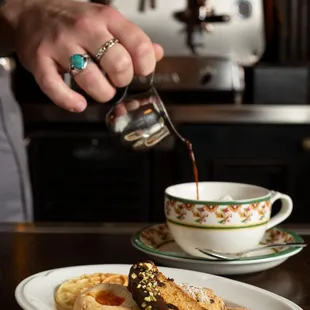 a person pouring coffee into a cup