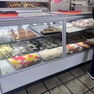 a woman looking at pastries in a display case