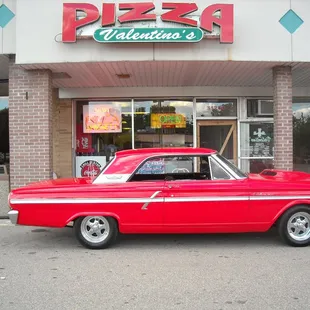 a red car parked in front of a pizza hut