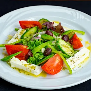 Greek Salad with locally grown tomatoes, Fresh Organic Greens, Cucumber, Kalamata Olives, Feta Imported from Greece, and house made dressing