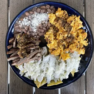 Chilaquiles verdes, scramble's eggs, steak, and pinto beans