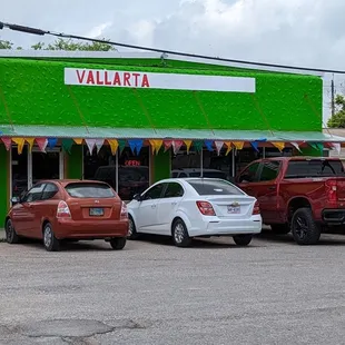 cars parked in front of a green building