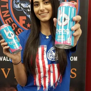 a woman holding two cans of energy drink
