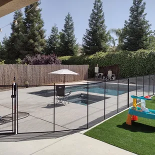 A pool fence separates the play areas from the pool area. The gate closes and locks automatically.