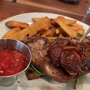 Open faced steak sandwich on focaccia bread with red wine tomatoes and a side of fries
