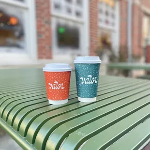 two cups of coffee on a bench