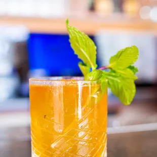 a glass of orange juice with a sprig of mint