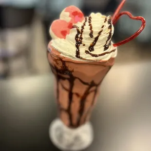 a chocolate milkshake topped with whipped cream and chocolate syrup