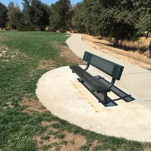 Small bench for sitting with a walking trail adjacent to the park