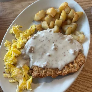 a plate of fried chicken with gravy and potatoes