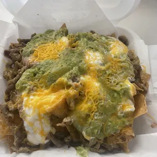 Super Nachos, chips, carne asada, sour cream, cheese, and guacamole.