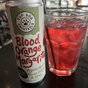 a can of blood orange margarita next to a glass of water