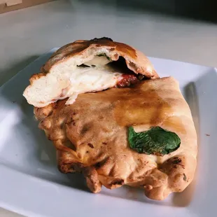 calzone with mozzarella, tomato, spinach, and sausage