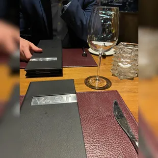 a person sitting at a table with a menu and a glass of wine