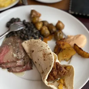 Steak with garlic butter, black beans, fried catfish taco, brussel sprouts, potatoes.