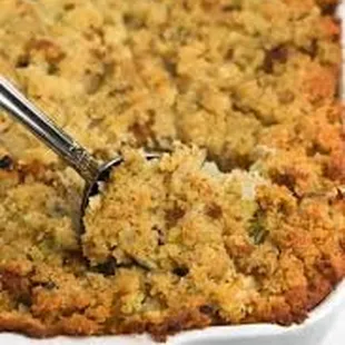 a close up of a serving spoon scooping up a cornbread casserole