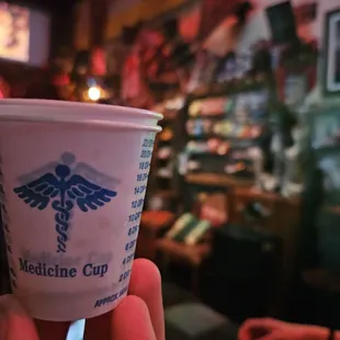 a hand holding a cup of medicine cup