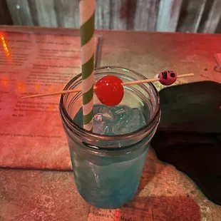 a blue drink with a cherry on a stick