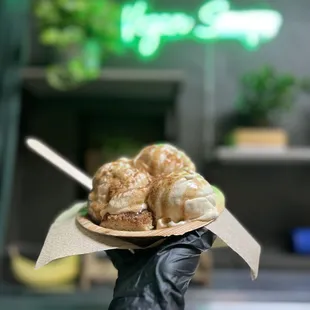 a person holding a paper plate of doughnuts