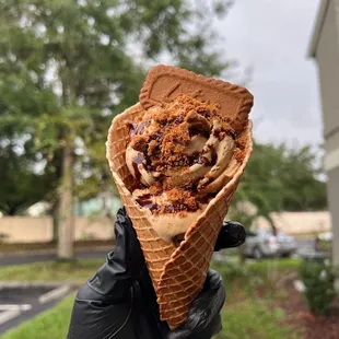 a hand holding a cone of ice cream