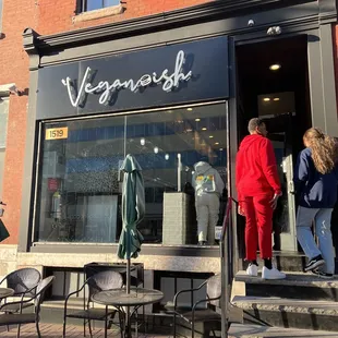 a couple of people standing outside of a restaurant