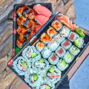 a person holding a tray of sushi