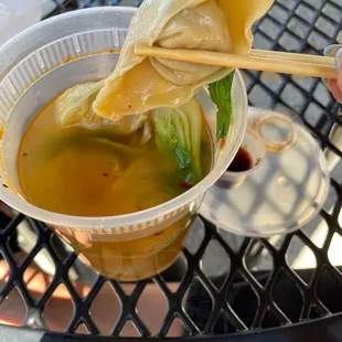a bowl of soup with chopsticks